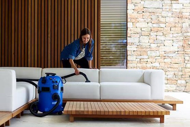 Woman cleaning couch with Wet and Dry vacuum cleaner